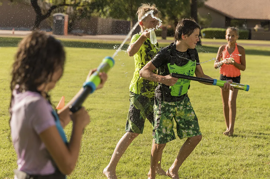 Kids in water battle with water pistols and collection vests